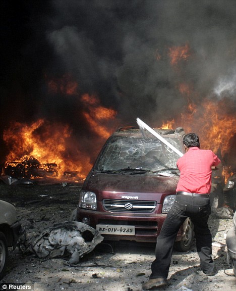 Bomb site: A man breaks the windscreen of a car, thought to be helping people trapped inside, after the bomb blast in Guwahati, the main city of India's troubled northeastern Assam state