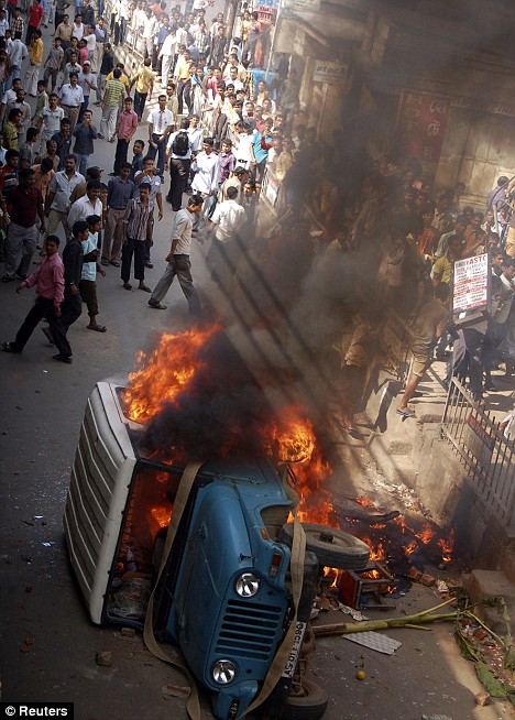 People look at a burning government vehicle. It is thought this vehicle was set alight by the crowd in anger after the bombings