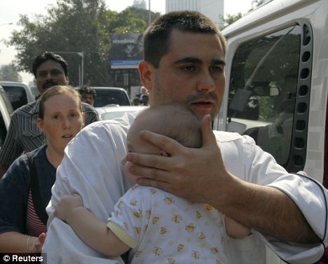 Safe at last: A guest emerges from the Oberoi hotel clutching a tiny baby